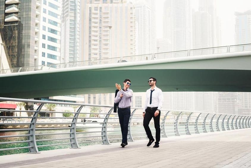 Dvaja podnikatelia sa rozprávajú pri prechádzke v Dubai Marina.