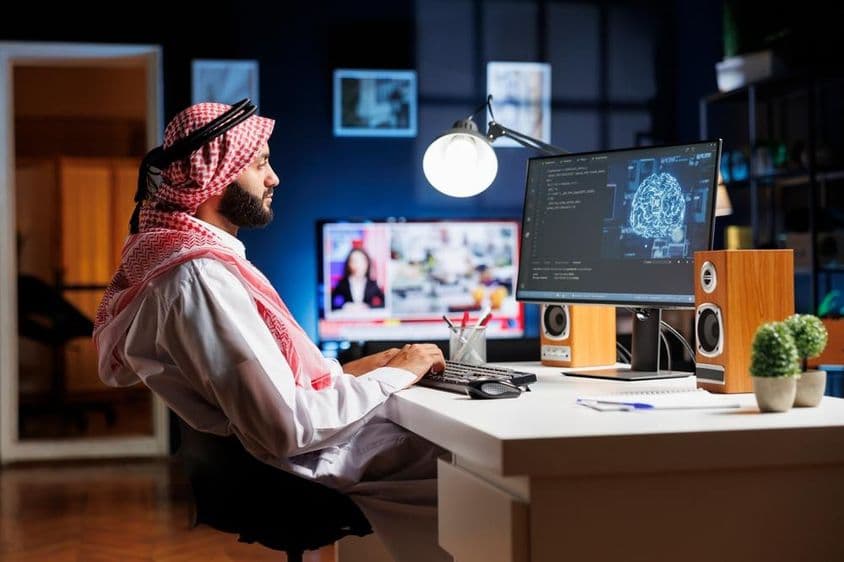 Profesionálny muž v arabskom odeve pracujúci na futuristickom užívateľskom rozhraní.