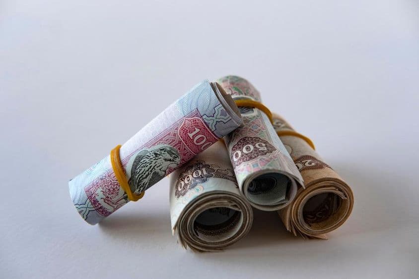 Kolekcia dirhamovej meny a mincí SAE zvinutých a naskladaných.