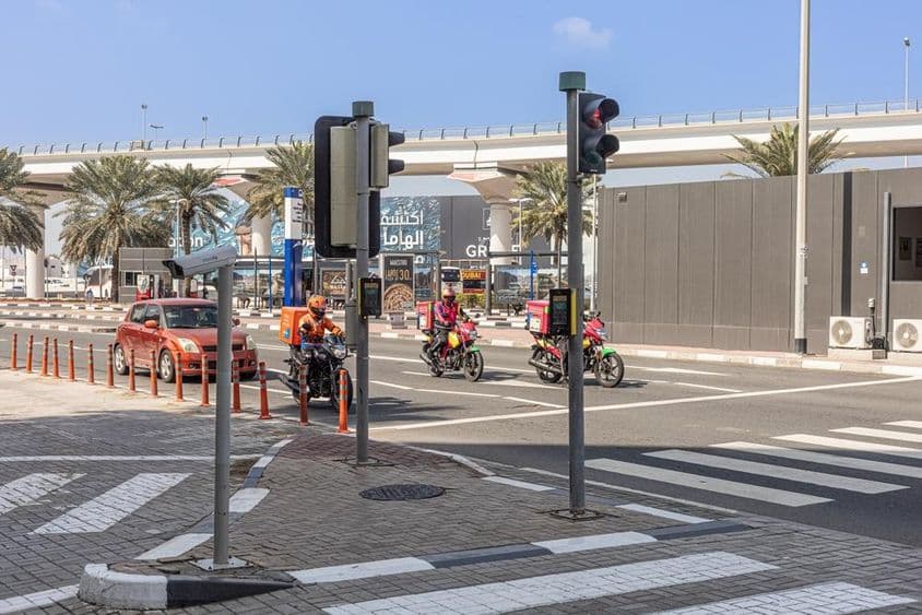 Tri motocykle a auto zastavujú na prechode pre chodcov na ceste Sheikh Zayed.