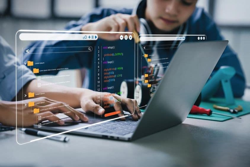 Tínedžerskí študenti pracujú na domácich úlohách zahŕňajúcich robotické ramená a robotické autá.