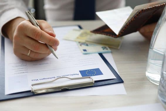 Muž držiaci pas a vkladá osobné údaje do žiadosti o schengenské víza.