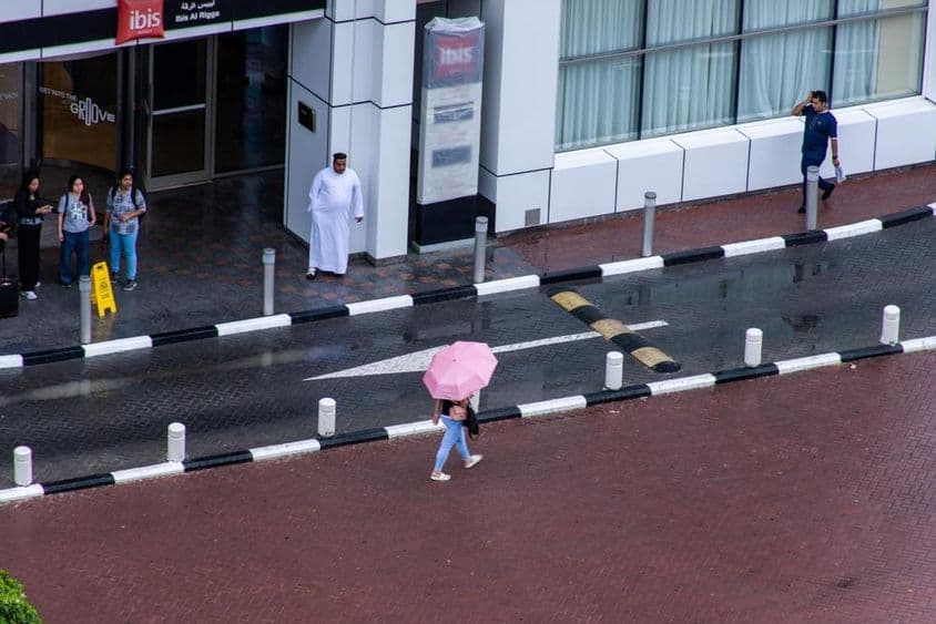 Dievča s dáždnikom kráčajúce v daždi v meste Dubaj.