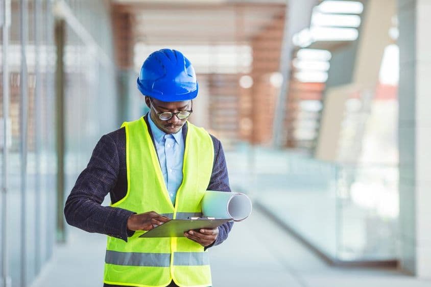 Mladý stavebný inžinier analyzujúci papierové štatistiky.