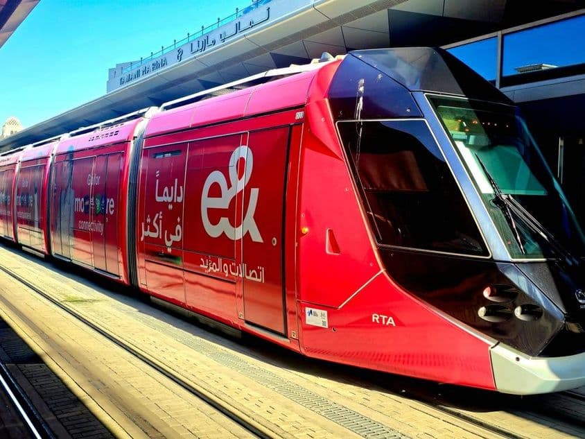 Červená tramvaj zaparkovaná na nástupišti s veľkými oknami a elegantným dizajnom.