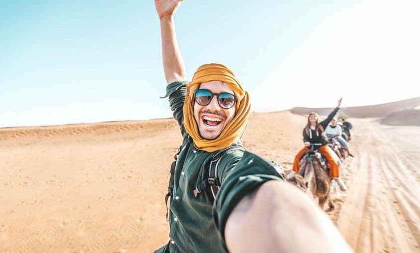 Šťastný turista si užíva jazdu na ťave v púšti.