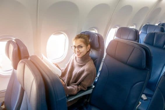 Ázijská žena číta časopis v lietadle.