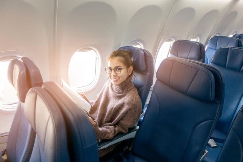 Ázijská žena číta časopis v lietadle.