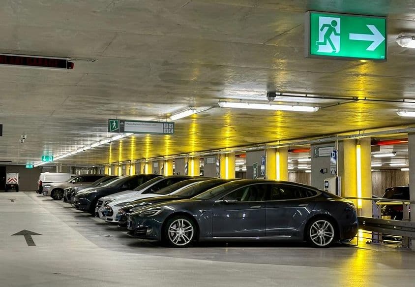 Žlté neónové svetlá osvetľujú miesta vyhradené pre elektrické vozidlá.