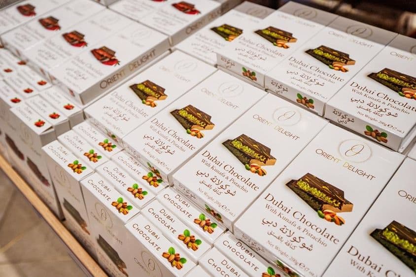 Dubajské čokoládové tyčinky plnené kunafa a pistáciami naskladané na poličke obchodu.