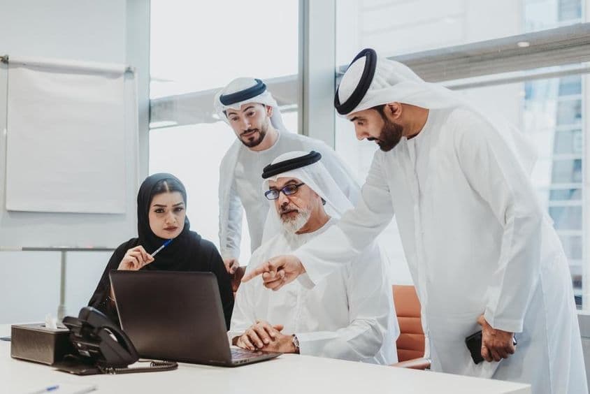 Podnikatelia v emirátskom odeve na stretnutí v kancelárii v Dubaji.