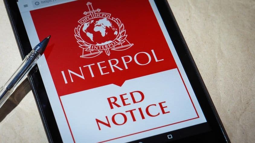 Červené oznámenie Interpolu zobrazené na obrazovke mobilného telefónu.