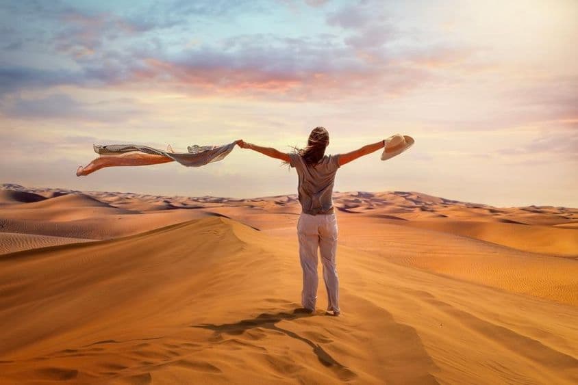 Turistka stojí v Červenej púšti, Dubaj, máva šatkou v horúcom vzduchu.