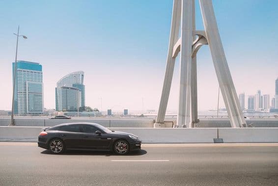 Čierne auto Porsche Panamera sa pohybuje po ulici v Dubaji.