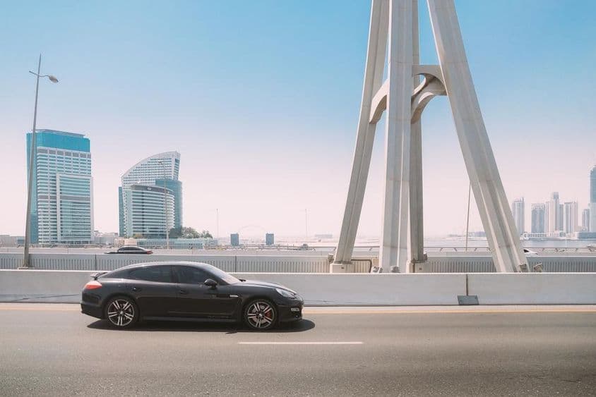 Čierne auto Porsche Panamera sa pohybuje po ulici v Dubaji.