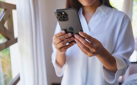 Žena používa iPhone 15 Pro Max doma.