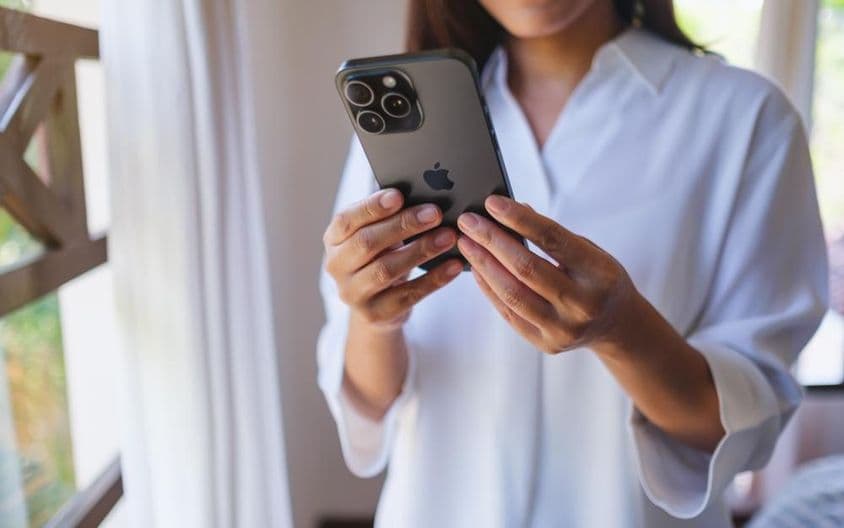 Žena používa iPhone 15 Pro Max doma.