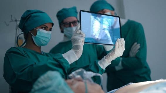 Profesionálny medicínsky tím diskutuje a prezerá röntgen pacienta s pneumóniou.