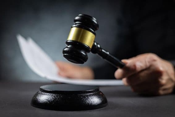 Sudca oznamuje rozsudok s dokumentom v súdnej sieni.