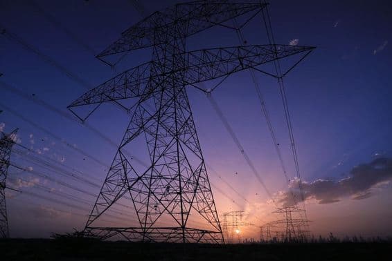 Vysokonapäťové veže pri západe slnka s pohľadom na panorámu Dubaja.