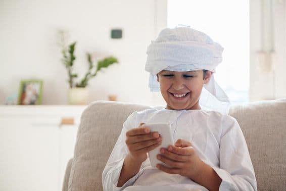 Arabský chlapec používajúci smartfón doma.