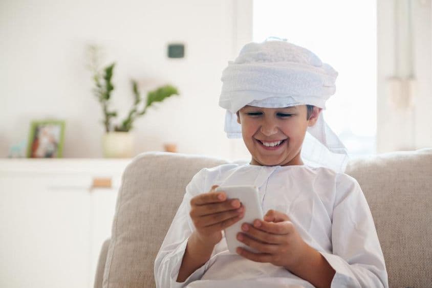 Arabský chlapec používajúci smartfón doma.