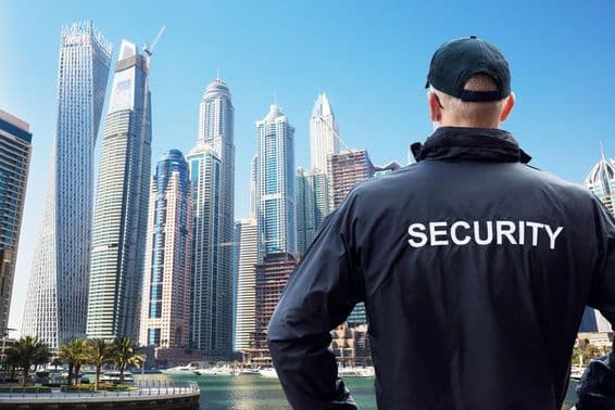 Mužský bezpečnostný strážca stojí a sleduje mestskú krajinu zozadu.