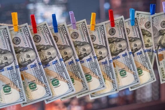 Bankovka 100 amerických dolárov zavesená na šnúre s drevenými štipcami.