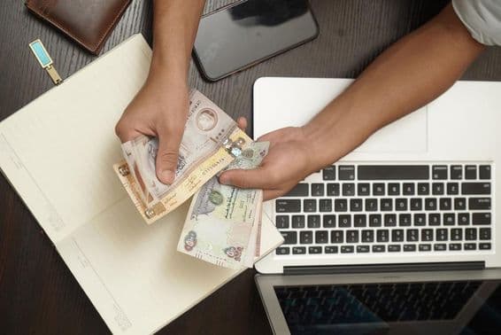 Muž počítajúci zväzok bankoviek SAE dirhamov.