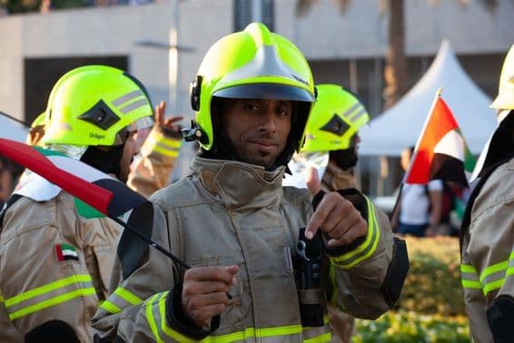 UAE hasiči kráčajú s vlajkou Emirátov pri príležitosti národného sviatku.