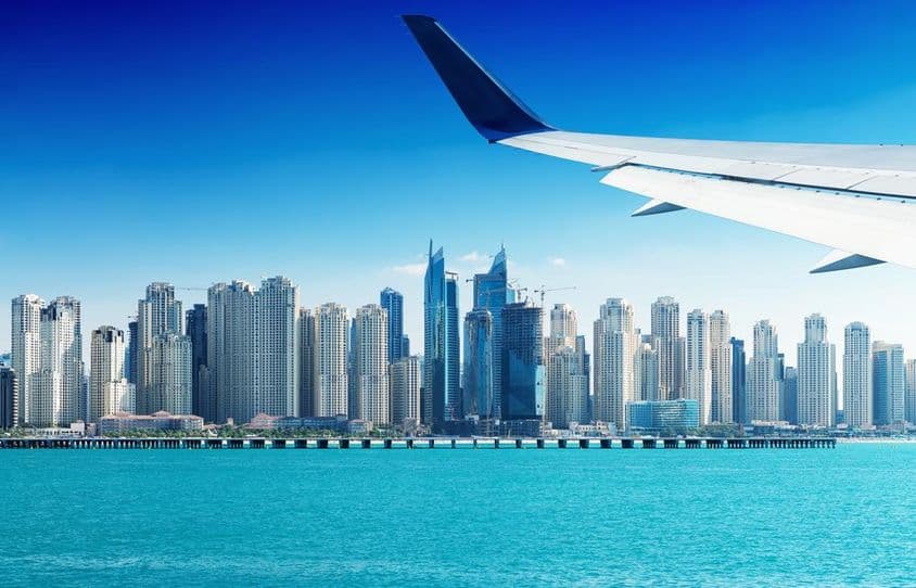 Lietadlo letiace nad mrakodrapmi v Dubaji.