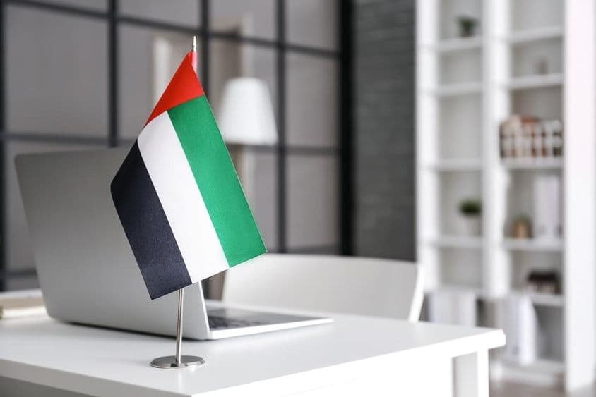 Vlajka Spojených arabských emirátov na stole v modernom kancelárii.
