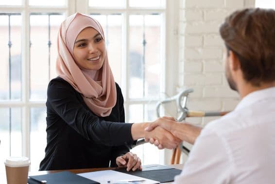 Arabská manažérka pre ľudské zdroje v hidžábe podáva ruku mužskému uchádzačovi o prácu.