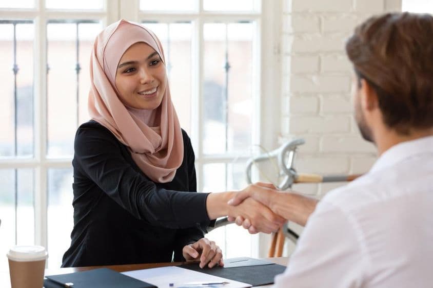 Arabská manažérka pre ľudské zdroje v hidžábe podáva ruku mužskému uchádzačovi o prácu.