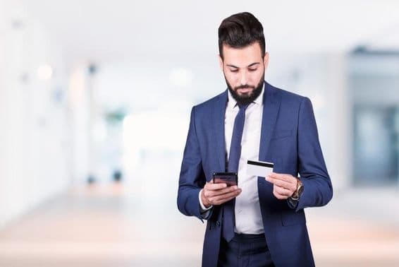 Arabský podnikateľ držiaci smartfón a kreditnú kartu.