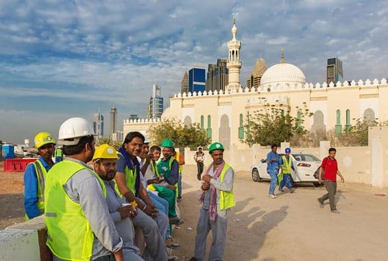 Stavební robotníci oddychujú vedľa mešity v modernom centre Dubaja.