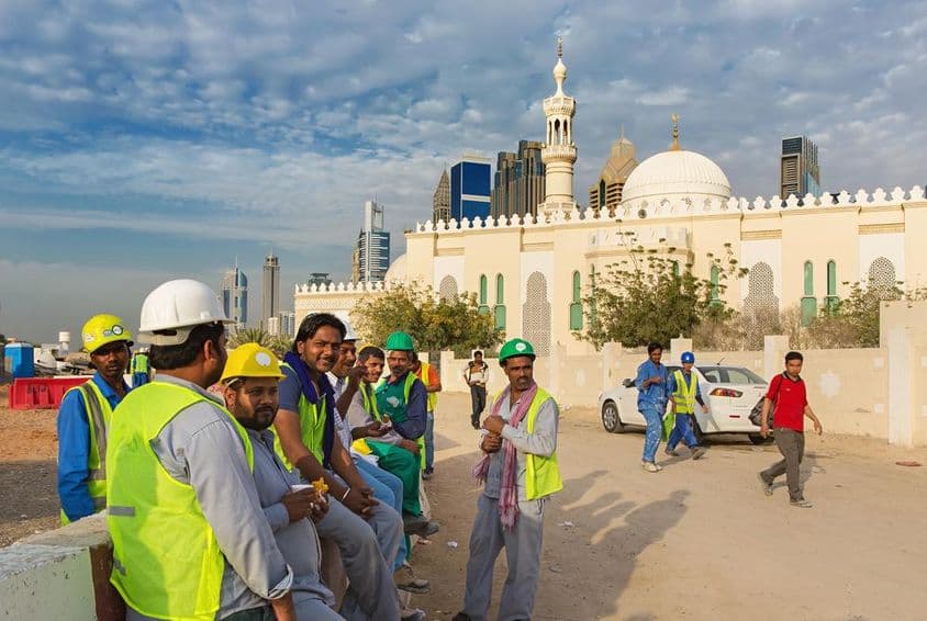 Stavební robotníci oddychujú vedľa mešity v modernom centre Dubaja.