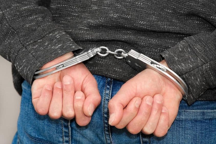 Zločinec v putách zatknutý pre zločiny.