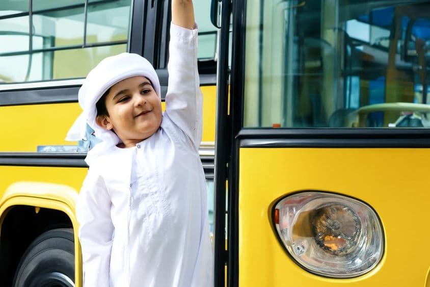 Arabský žiak pri žltom školskom autobuse.