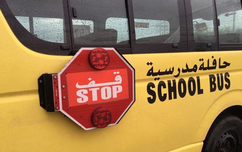 Prázdny školský autobus s červeným varovným znamením stop.