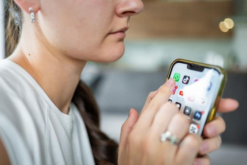 Žena držiaca iPhone s aplikáciou chatovacej aplikácie WhatsApp na obrazovke.