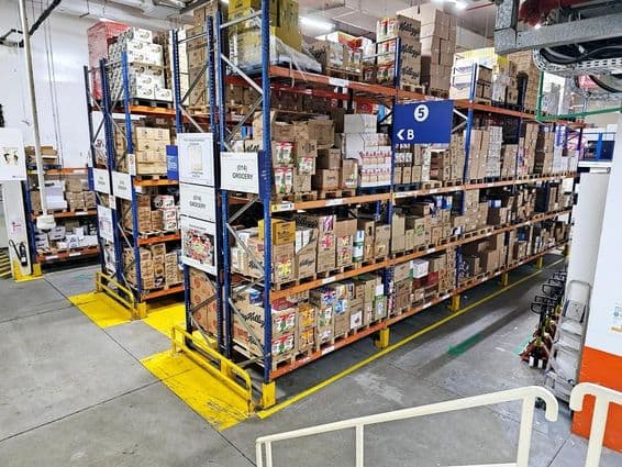 Sklad so systémami regálov, označené kategórie výrobkov a bezpečnostné značky uľahčujúce plynulý chod.