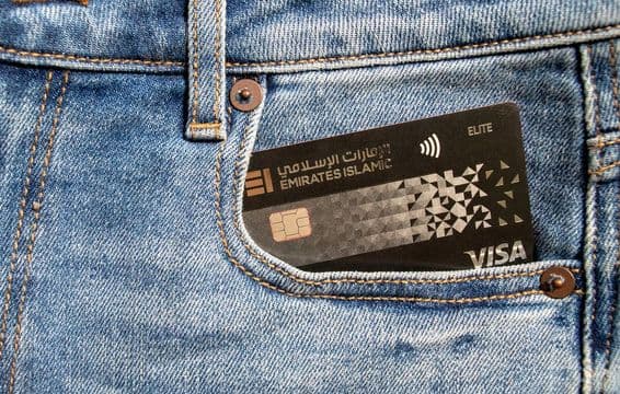 Plastová Visa kreditná karta Islamskej banky emirátov vo vrecku džínsov.