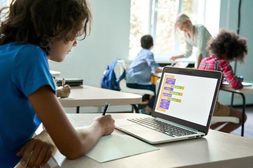 Študent strednej školy používa laptop na zadávanie kódovacích dát.