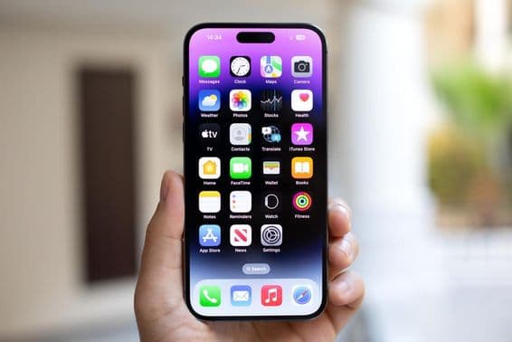 Muž držiaci iPhone 15 Pro Max s iOS 17 na obrazovke.