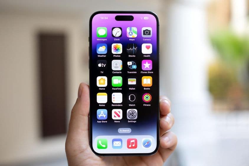 Muž držiaci iPhone 15 Pro Max s iOS 17 na obrazovke.