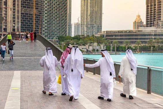Arabi v tradičnom bielom oblečení kráčajúci v centre Dubaja.