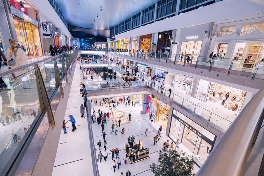 Interiér Dubajského obchodného centra s rôznymi obchodmi a návštevníkmi.