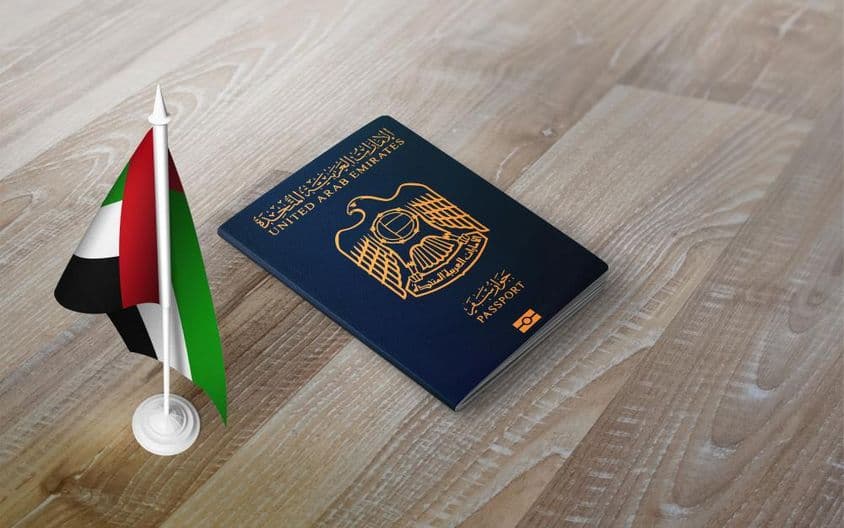 Pas Spojených arabských emirátov na drevenom povrchu s národnou vlajkou.