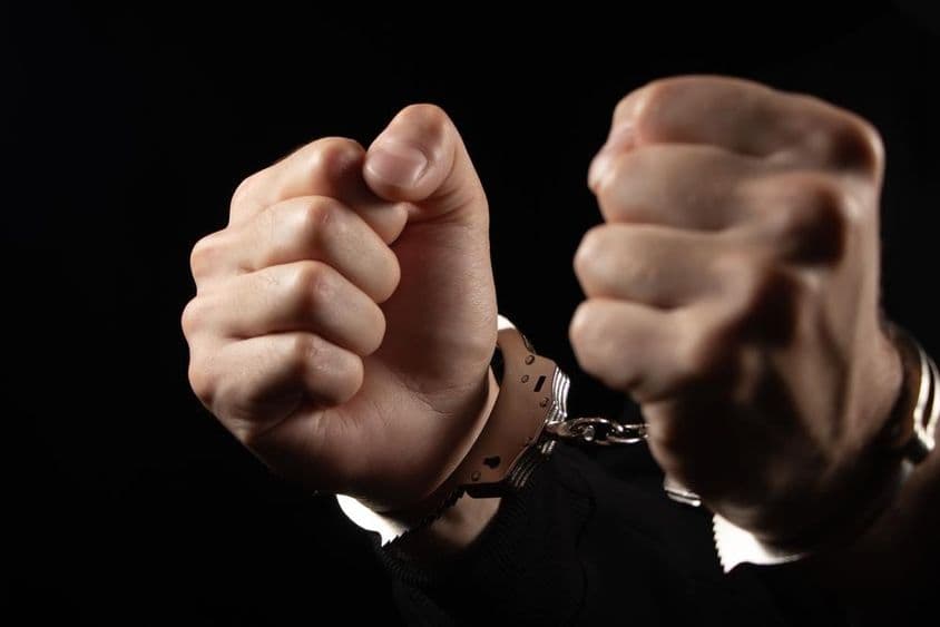 Muži v putách zatknutí za zločiny.